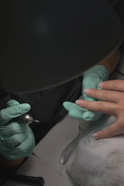 Vrouw handen ontvangen een manicure in schoonheidssalon. Nagelvijl. Close-up, selectieve focus. — Stockfoto