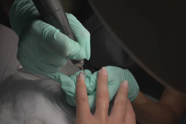 Mains de femme recevant une manucure dans un salon de beauté. Classement des ongles. Gros plan, focus sélectif. — Photo