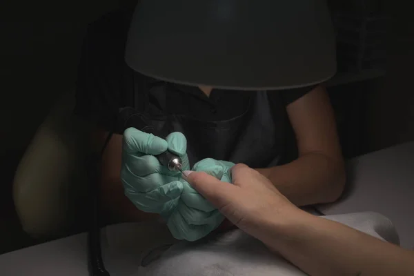 Mãos de mulher que recebem uma manicura no salão de beleza. Arquivamento de unhas. Close up, foco seletivo. — Fotografia de Stock