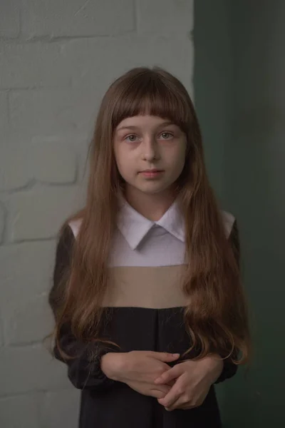Niña colegiala de pie. Niño de 9 años colegiala en un vestido de escuela con pelo castaño . — Foto de Stock