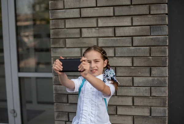 귀여운 십 대 소녀 가 밖에서 셀카를 들고 웃고 있었습니다. 휴대 전화로 자화상을 찍는 아이입니다. 기술 — 스톡 사진