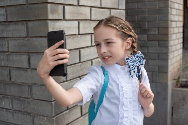 Gülümseyen güzel ergen kız dışarıda selfie çekiyor. Çocuk cep telefonuyla kendi portresini çekiyor. teknoloji