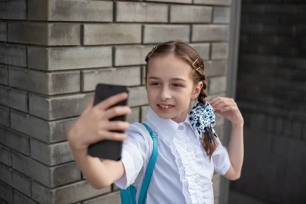 Sorrindo beatiful menina pré-adolescente tomando uma selfie ao ar livre. Criança a tirar um auto-retrato com telemóvel. tecnologia — Fotografia de Stock