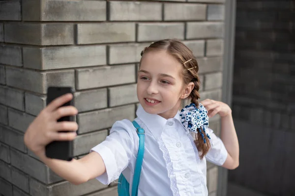 Sorrindo beatiful menina pré-adolescente tomando uma selfie ao ar livre. Criança a tirar um auto-retrato com telemóvel. tecnologia — Fotografia de Stock