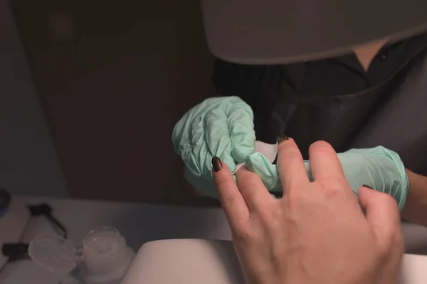 Mãos de mulher que recebem uma manicura no salão de beleza. Arquivamento de unhas. Close up, foco seletivo. — Fotografia de Stock