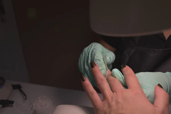 Mãos de mulher que recebem uma manicura no salão de beleza. Arquivamento de unhas. Close up, foco seletivo. — Fotografia de Stock
