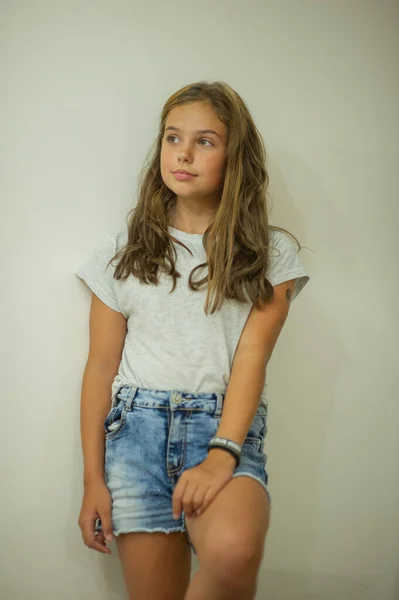 Πορτρέτο του ένα κομψό νεαρό όμορφο κορίτσι χαμογελώντας σε ένα γκρι T-shirt σε λευκό φόντο, φυσική εμφάνιση, μακριά καστανά μαλλιά, τζιν, casual στυλ — Φωτογραφία Αρχείου
