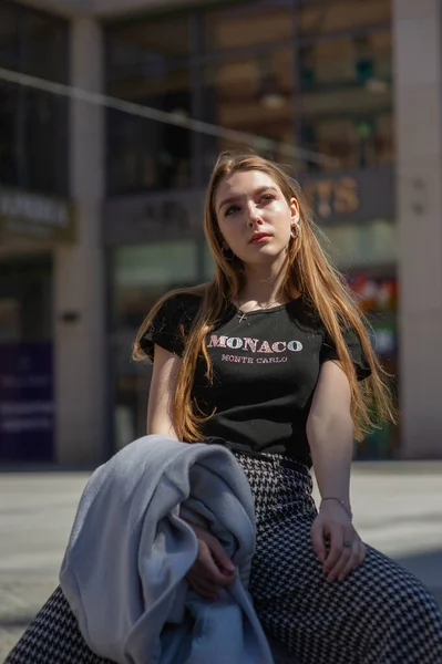 Una joven con una camiseta negra y pantalones grises es fotografiada en la calle. Hermosa mujer en un paseo por la ciudad — Foto de Stock
