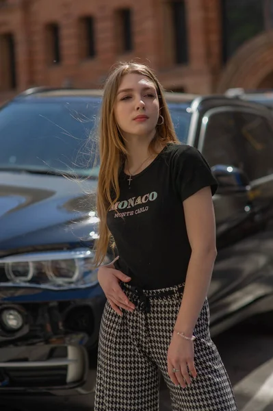 Una joven con una camiseta negra y pantalones grises es fotografiada en la calle. Hermosa mujer en un paseo por la ciudad — Foto de Stock