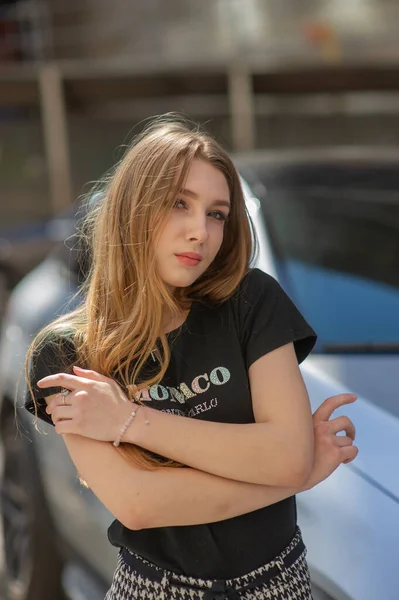 Una giovane ragazza con una maglietta nera e pantaloni grigi è fotografata per strada. Bella donna in una passeggiata in città — Foto Stock