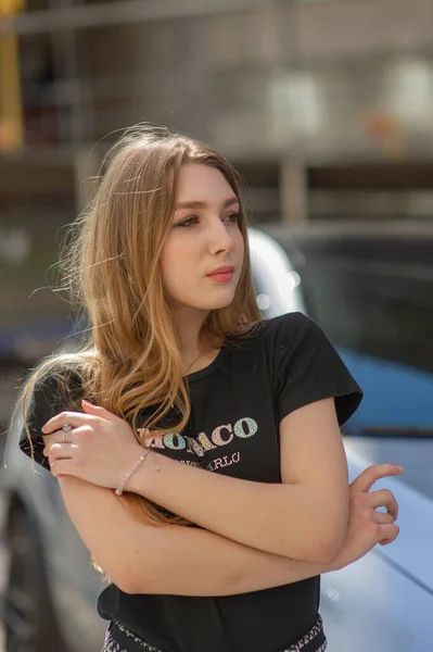 Una giovane ragazza con una maglietta nera e pantaloni grigi è fotografata per strada. Bella donna in una passeggiata in città — Foto Stock