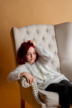 9 yaşında güzel bir kız. Stüdyoda sandalyede oturan 9 yaşındaki bir kız.