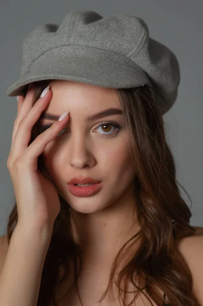 Glamoroso jovem mulher usa vestido elegante posando com cabelo agitado na parede cinza — Fotografia de Stock