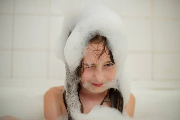 Rapariga dentro do banho. Uma menina toma banho em uma banheira com espuma . — Fotografia de Stock