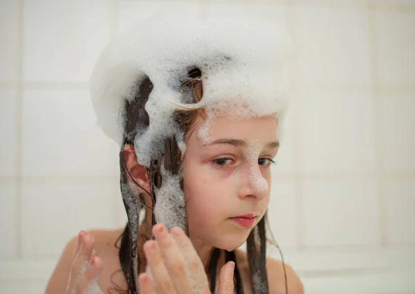 Rapariga dentro do banho. Uma menina toma banho em uma banheira com espuma . — Fotografia de Stock