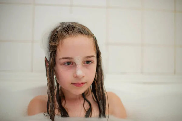 Rapariga dentro do banho. Uma menina toma banho em uma banheira com espuma . — Fotografia de Stock