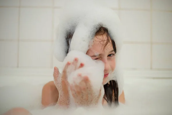 Jovencita dentro del baño. Una niña se baña en una bañera con espuma . —  Fotos de Stock