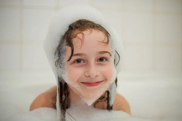 Rapariga dentro do banho. Uma menina toma banho em uma banheira com espuma . — Fotografia de Stock