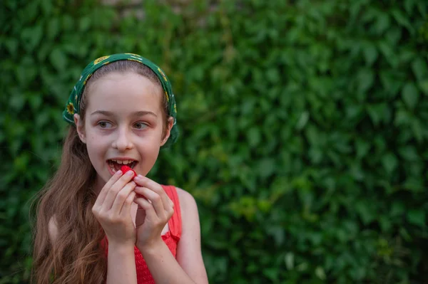 Klein meisje op straat tegen een achtergrond van groen gebladerte. Meisje met lang haar. Kind van 9-10 jaar — Stockfoto