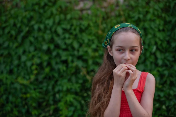 Little girl on the street against a background of green foliage. Girl with long hair. Child 9-10 years old — 스톡 사진