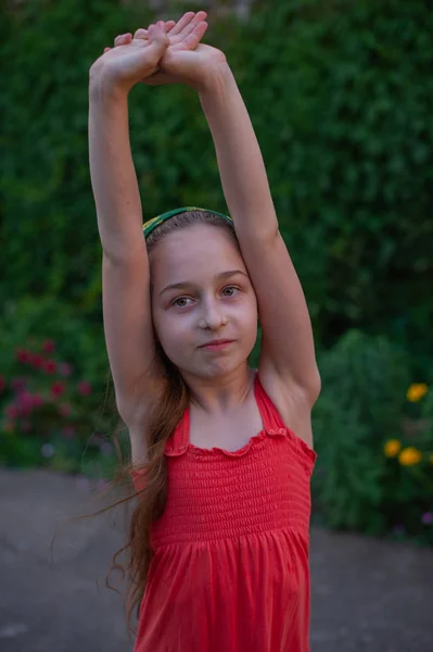 Menina na rua contra um fundo de folhagem verde. Menina com cabelo comprido. Criança 9-10 anos — Fotografia de Stock