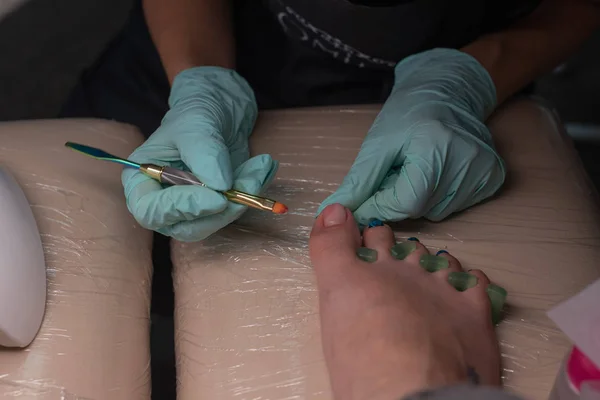 Master chiropody applying gel nail polish. Spa. Concept body care.