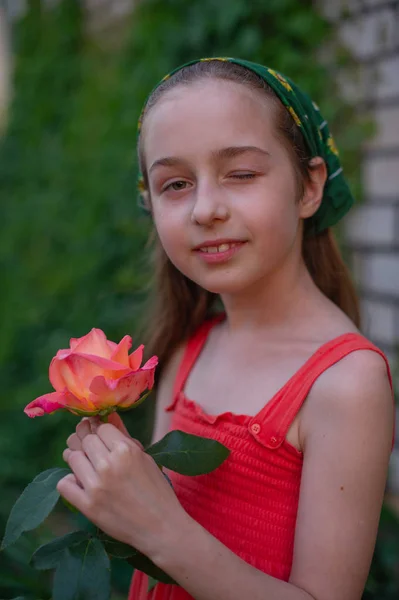 Holčička na ulici na pozadí zeleného listí. Dívka s dlouhými vlasy. Dítě 9-10 let — Stock fotografie