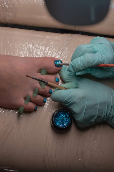Master chiropody applying gel nail polish. Spa. Concept body care.