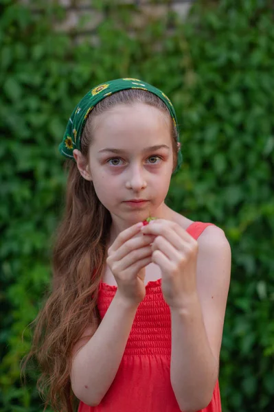 Holčička na ulici na pozadí zeleného listí. Dívka s dlouhými vlasy. Dítě 9-10 let — Stock fotografie