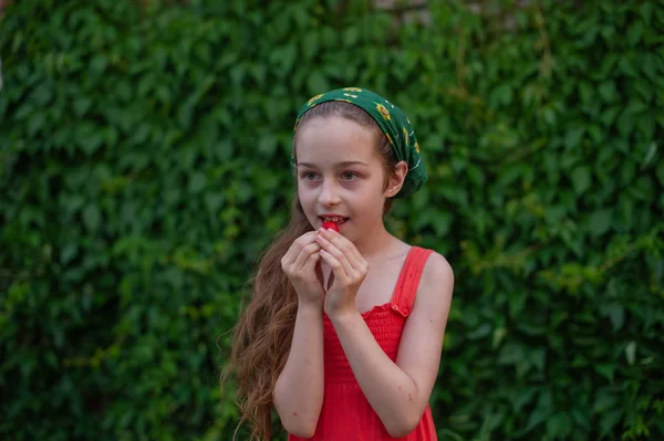 Holčička na ulici na pozadí zeleného listí. Dívka s dlouhými vlasy. Dítě 9-10 let — Stock fotografie