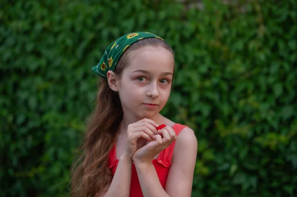 Egy kislány az utcán, zöld lombozat hátterében. Hosszú hajú lány. 9-10 éves gyermek — Stock Fotó