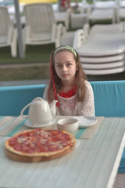 カフェでピザと若い女性の肖像画。女の子9歳食べるピザで夏のカフェの休暇 — ストック写真