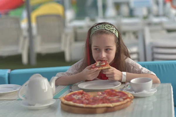 Retrato de mujer joven con pizza en la cafetería. Chica de 9 años come pizza en un café de verano de vacaciones —  Fotos de Stock