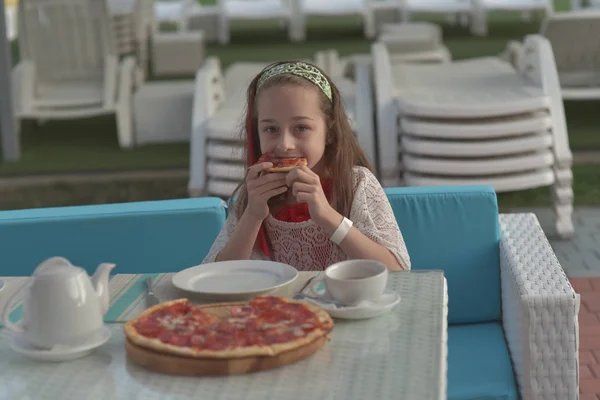 Egy fiatal nő portréja pizzával a kávézóban. 9 éves lány pizzát eszik egy nyári kávézóban nyaralni — Stock Fotó