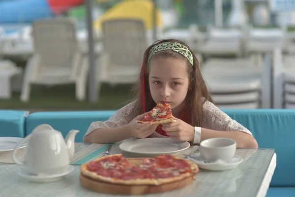 咖啡馆里拿着披萨的年轻女人的画像。9岁的女孩在暑期咖啡馆里吃披萨 — 图库照片