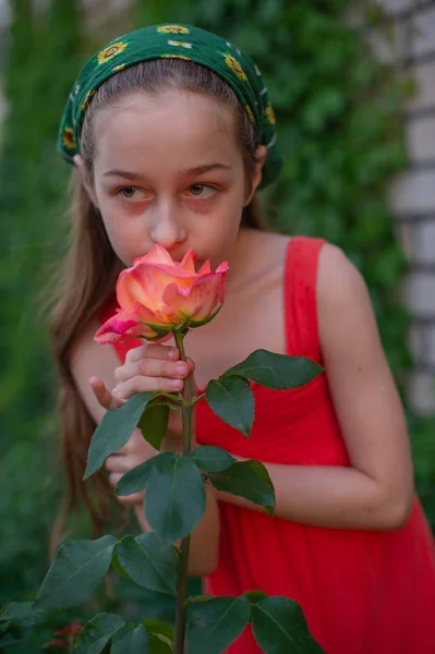 Little girl on the street against a background of green foliage. Girl with long hair. Child 9-10 years old — Stock Photo, Image