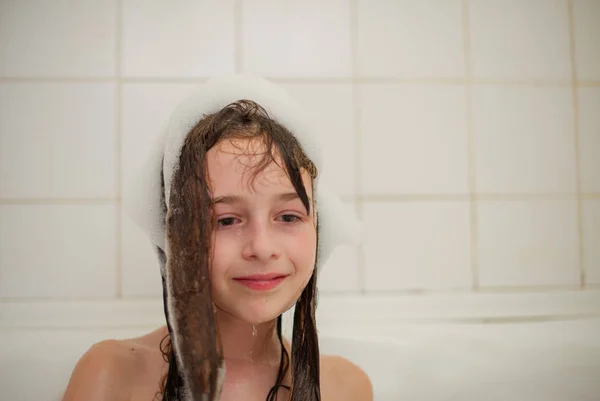 Jeune fille dans le bain. Une petite fille se baigne dans une baignoire en mousse . — Photo