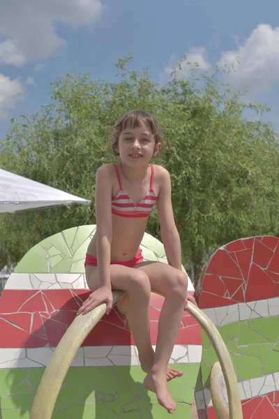 Uma menina está descansando no verão no parque aquático. O bebé nada na piscina. Menina 9 anos de idade descansando na água . — Fotografia de Stock