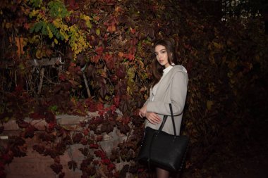 Gece şehrinde ceketli hoş bir kızın portresi. Esmer kız ve gece şehri.