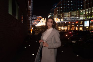 Gece şehrinde ceketli hoş bir kızın portresi. Esmer kız ve gece şehri.