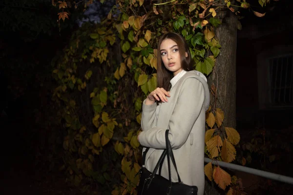 Portrait d'une gentille fille en manteau chaud dans une ville nocturne. Brunette fille et nuit ville . — Photo
