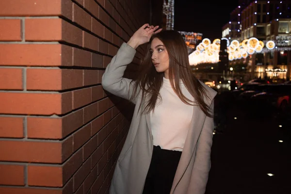 Retrato de una buena chica con un abrigo cálido en una ciudad nocturna. Chica morena y ciudad de la noche . — Foto de Stock