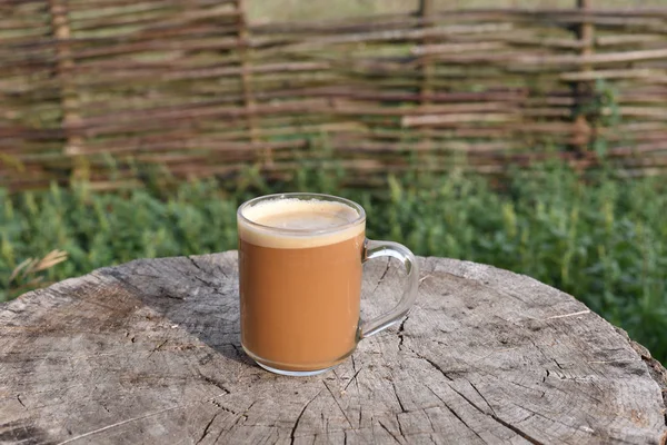 Un bicchiere di caffè chiaro sulla terrazza in legno. Sullo sfondo c'è una risaia verde . — Foto Stock