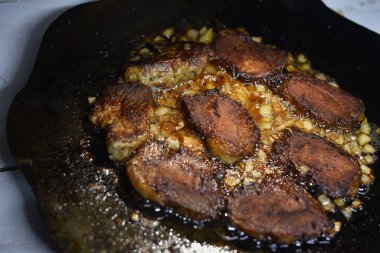 Pirzolalar ateşte kızardı. Tavada et pişiriyor.