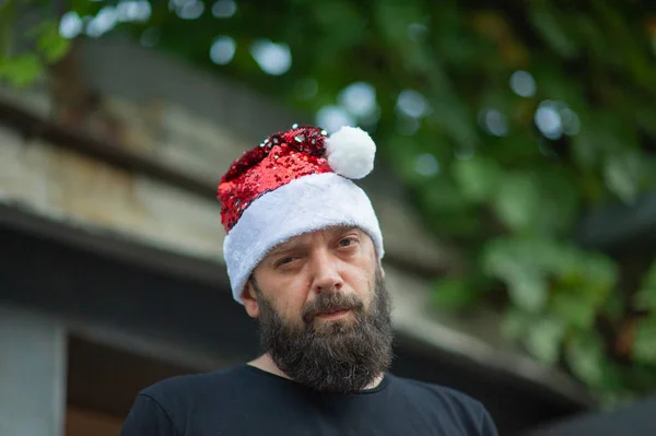 Santa Claus caminando por la calle de la ciudad. Hombre con barba en la calle en el verano en un sombrero de Santa Claus . —  Fotos de Stock