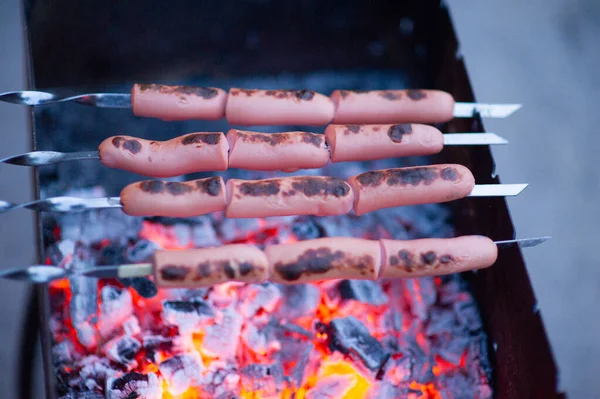 Würstchen auf dem Grill. im Hintergrund im Lagerfeuer. — Stockfoto