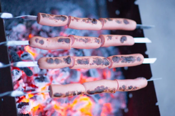 Sausages on a grill. In the background in bonfire. — Stock Photo, Image