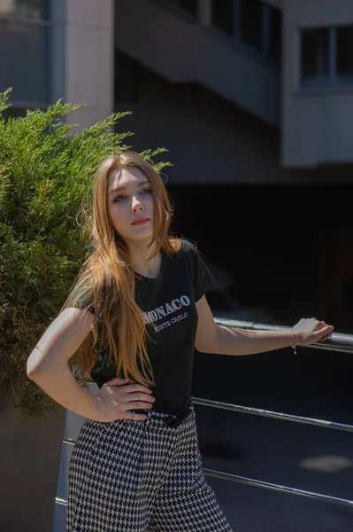 Mujer joven glamurosa lleva vestido de moda posando con el pelo ondulado en la pared gris —  Fotos de Stock