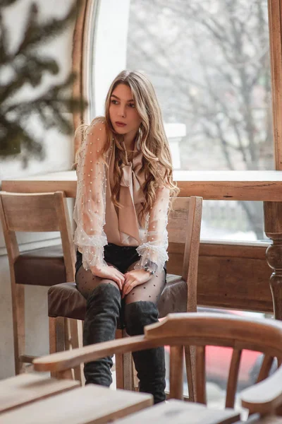 Bella ragazza caucasica in camicetta beige, rossetto seducente e capelli ondulati in piedi nel caffè. Ragazza in camicetta beige — Foto Stock
