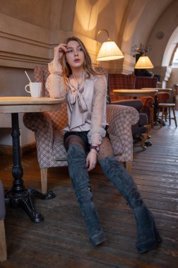 Kafedeki genç ve güzel kadın. Grunge. Kafede bej bluzlu bir kız. Kafede kahve içen bir kız. Latte, cappuccino